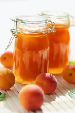 Kayısı reçeli. Cam kavanozlarda portakal reçeli, ahşap bir masada taze olgun kayısılar. 