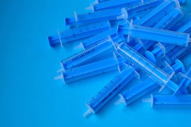 Tıp ve sağlık konsepti. Mavi plastik şırıngalar mavi arka planda yakın plan