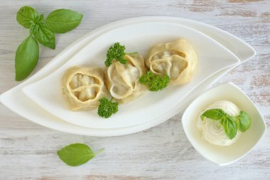 Hamur köftesi. Sebzeli arka planda yuvarlak tabakta yeşillik olan ev yapımı Manty.