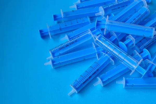 Medicine and health concept. Blue plastic syringes close-up on a blue background