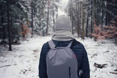 Sırt çantalı adam kışın ormanda yürüyor.