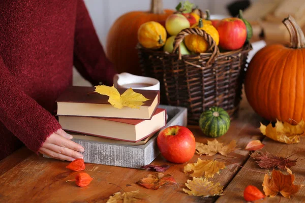 books, cup of tea and pumpkins on table