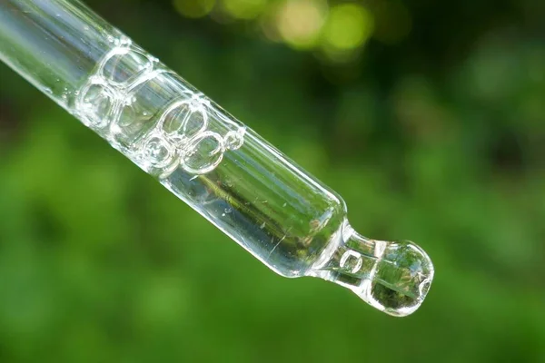 Essential oil in pipette.Oil herbal extract.Herbal extract in a pipette on a blurred green background
