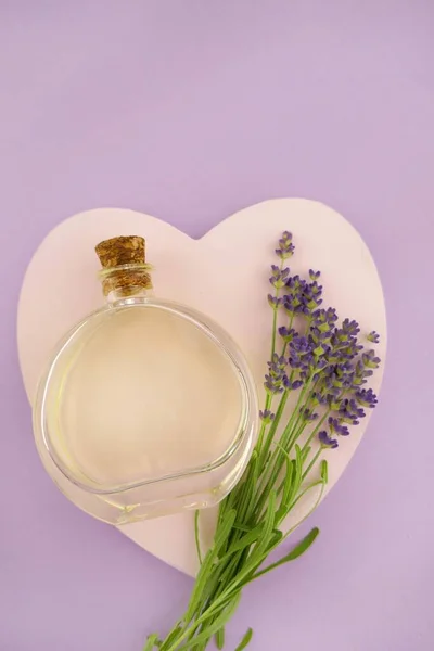 玻璃瓶中的薰衣草精油和粉色与紫色混合背景的薰衣草花 — 图库照片
