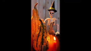 Siyah şapkalı, balkabaklı ve yanan mumlu bir cadılar bayramı. Dikey video. 4k görüntü