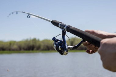 Gölde balık tutmak. Gölün arka planında bir balıkçının elinde olta ile olta. Bir balıkçılık geçmişi.