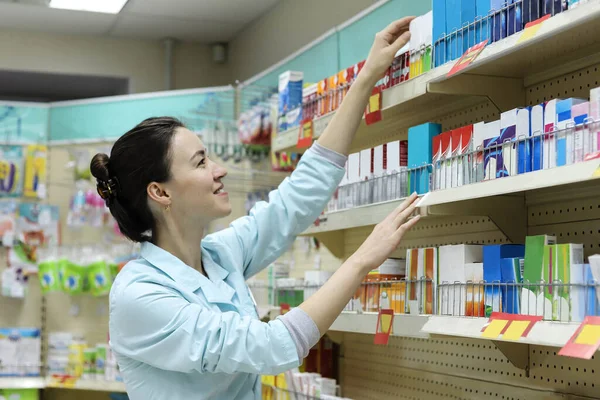 Vrouwelijke Apotheker Trekt Uit Plank Medicatie — Stockfoto