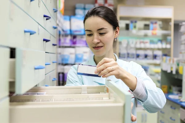 Woman pharmacist looking for the necessary medicine in the box