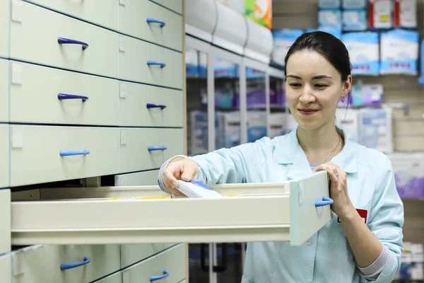 Woman pharmacist looking for the necessary medicine in the box