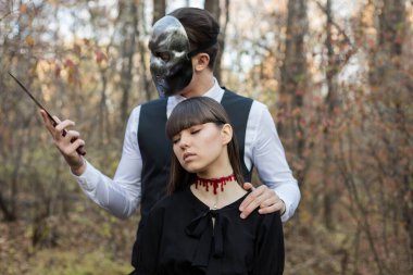 Maskeli adam bir kızı bıçakla tehdit ediyor. Maskeli manyak ormanda bir kıza saldırdı..