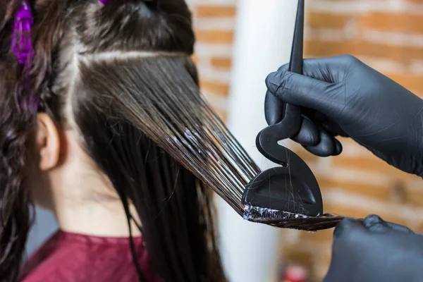 Keratin hair strengthening close-up. The process of applying liquid keratin using a special hairdressing brush. Hair straightening and strengthening.