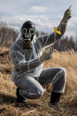 Gaz maskeli yeşil kulaklı bir uzaylı, çiçeğe şaşkınlıkla bakıyor. Bir uzaylı dünyayı inceliyor. UFO.