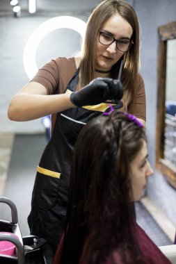 Usta keratin teknolojisi uzmanı bunu düzeltmek için müşterinin kıvırcık saçlarına sıvı keratin uyguluyor. Keratin saç düzleştirme işlemi. Saç bakımı. Saç restorasyonu.