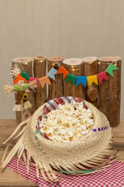 Hasır şapkayla servis edilen patlamış mısır ve arka planda Haziran dekorasyonu. Festa Junina: Tipik Brezilya Haziran partisi.