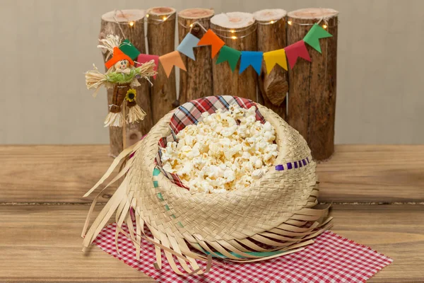 Hasır şapkayla servis edilen patlamış mısır ve arka planda Haziran dekorasyonu. Festa Junina: Tipik Brezilya Haziran partisi.