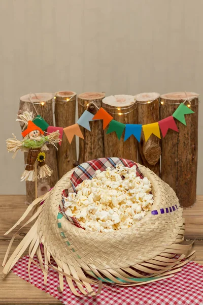 Hasır şapkayla servis edilen patlamış mısır ve arka planda Haziran dekorasyonu. Festa Junina: Tipik Brezilya Haziran partisi.