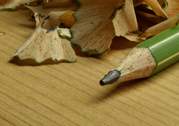 Macro photo of a green pencil with pencil shavings in the background