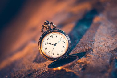 Bulanık arkaplana yakın çekilmiş eski bir cep saati.