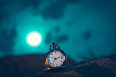 An old pocket watch photographed close to the blurred background clipart