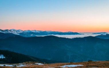 Romanya 'daki renkli sisli dağlarda görülebilir siluetlerle dağ sıraları. Tarcu Dağları.