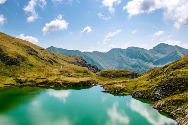 Buzul gölündeki dağların ve bulutların yansıması. Fotoğraf 03.09.2019 'da çekildi.