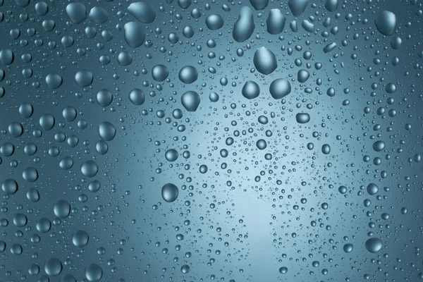 Drops of water on a blue glass texture background