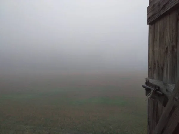 View on a foggy silent hill through a wooden window