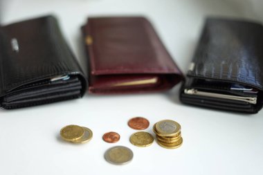 Üç cüzdan, siyah ve bordo, önünde bozuk paralar olan.