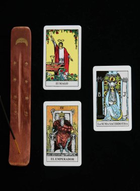 Tütsü masasının yanındaki tarot kartlarında altın ay ve siyah örtülü altın yıldızlar var.
