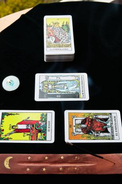 Koyu arkaplanda tarot kartları ve önlük mumları.