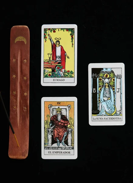 Tütsü masasının yanındaki tarot kartlarında altın ay ve siyah örtülü altın yıldızlar var.