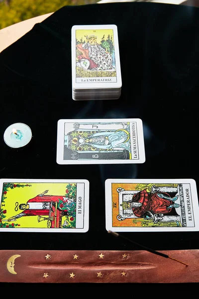 Koyu arkaplanda tarot kartları ve önlük mumları.