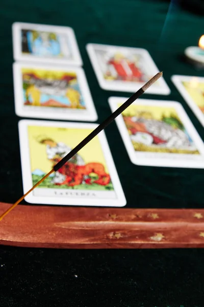 Koyu yeşil bir kumaş üzerinde tarot kartları. Kahverengi tütsü masasının yanında altın bir ay ve altın yıldızlı.