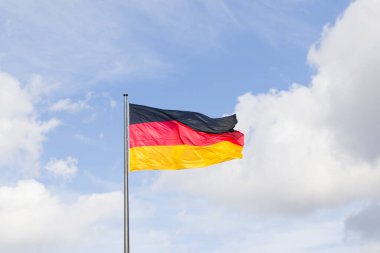 Almanya ulusal bayrağı, mavi gökyüzü arka planında kırmızı, siyah ve sarı renkler.