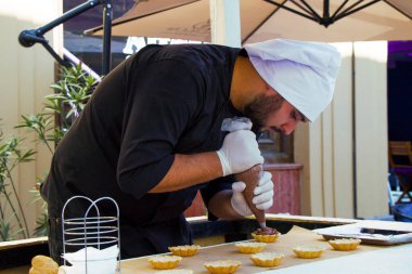 TBILISI, GEORGIA - 08 Ekim 2017: Şekerleme şefi tatlı sahnesi hazırlıyor, şef pasta süslüyor ve şehir festivalinde Tiflis caddesinde çalışıyor.