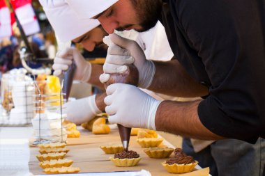 TBILISI, GEORGIA - 08 Ekim 2017: Şekerleme şefi tatlı sahnesi hazırlıyor, şef pasta süslüyor ve şehir festivalinde Tiflis caddesinde çalışıyor.