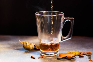 Masada sıcak içki, tarçın ve karanfilli rom ve çay, siyah arka planda..