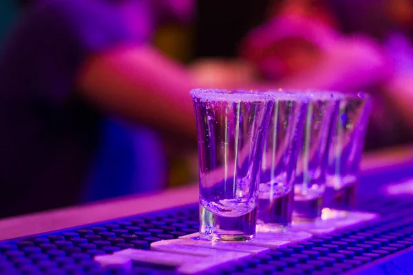 晚上派对桌上的龙舌兰酒镜头 背景上的人 第比利斯夜总会的酒精满满一杆蓝光 — 图库照片