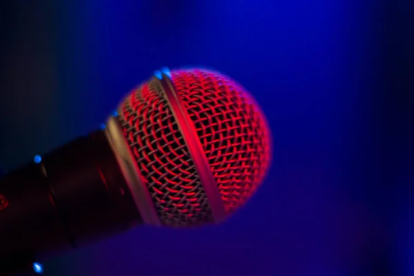 Microphone close-up and macro, musical and voice speak instrument on the blue background. Red led light.