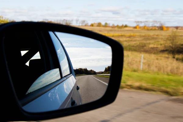 Road in car mirror reflection, highway and trees