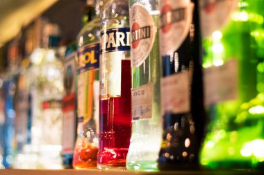 Martini ve diğer alkolikler içki şişelerini bar rafında içerler.