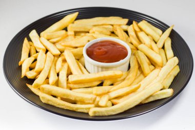 Siyah tabakta patates kızartması ve ketçap, beyaz arka plan.. 