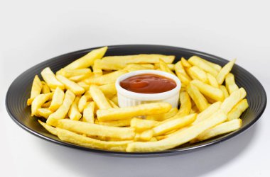 Siyah tabakta patates kızartması ve ketçap, beyaz arka plan.. 