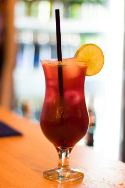 Barın masasında alkol, meyve suyu, limon ve buzlu renkli bir kokteyl..