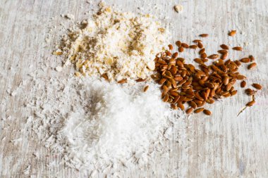 Hindistan cevizi, ekmek kırıntıları ve keten tohumları beyaz ahşap arka planda