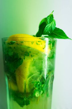 Bardakta mojito kokteyli, taze içecek, içmeye hazır, nane, limon ve limon, alkol ve buz küpleriyle. Yeşil renk. beyaz arkaplan.