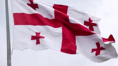 Gökyüzünde rüzgarda dalgalanan Gürcistan bayrağı.