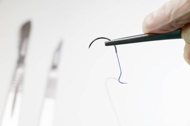 İnceleme kiti - Emilebilir dikiş, poliglikolik asit. Ameliyat ekipmanları, bıçak, iğne ve dikiş. Stüdyo çekimi.