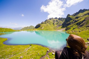 Georgia, Svaneti 'deki dağ vadisinde ve göl kenarındaki tarlada genç bir kadın.