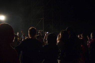 Canlı müzik konseri, gece hayatı ve kalabalık insanlar, ayakta durup müzik dinleyen genç yetişkinler. Karanlık ve aydınlık.